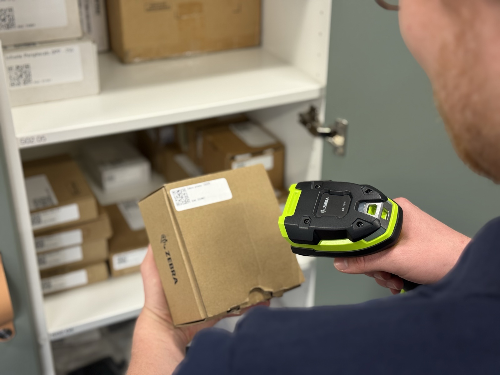 Warehouse worker scanning inventory with a Zebra scanner and iPhone